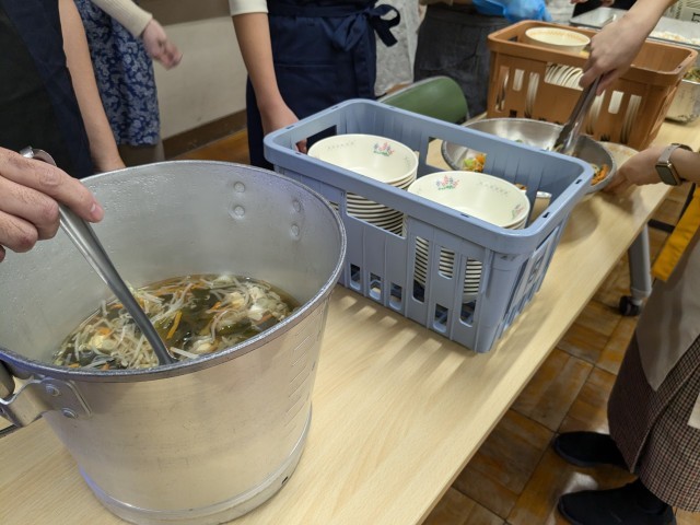 配膳の様子。あさり入りすまし汁とおかか和えを入れるところ。
