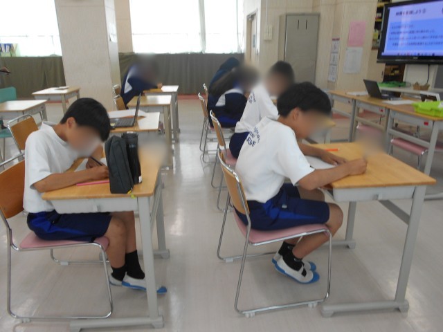 「時間を意識しよう」の活動で、用紙のマス目を色鉛筆で塗りながら、3分の長さを体感する生徒たち。前方の画面には活動の説明が映っている。