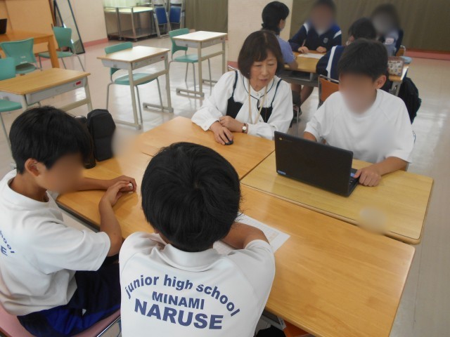グループでChromebookを使い、教員と一緒に学習計画を考える生徒たち。机の上には計画づくりのワークシートが置かれている。